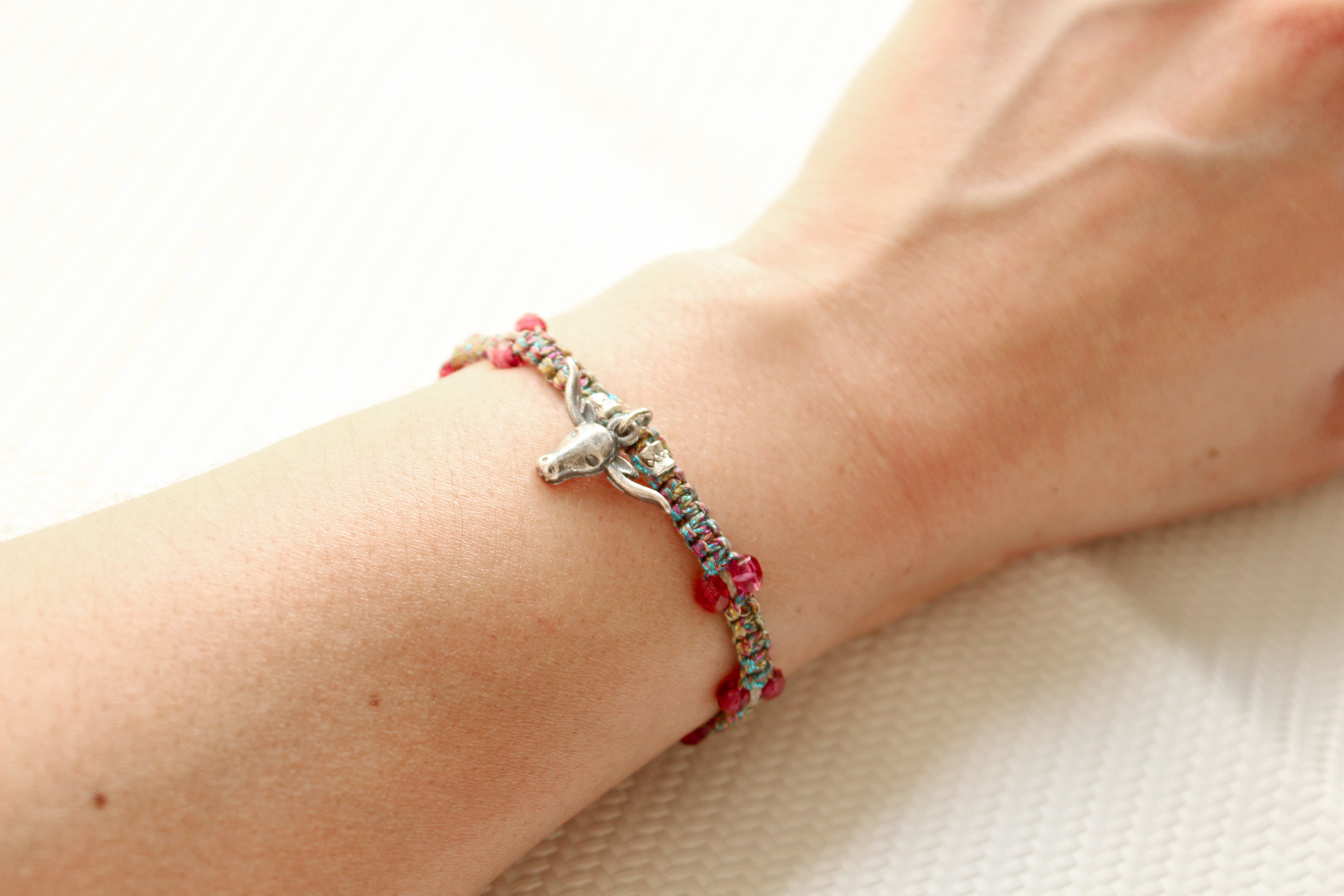 ORGADA's Bullia bracelet made of colourful waxed cords and a bull pendant in a macrame tecnique photographed on a wrist.